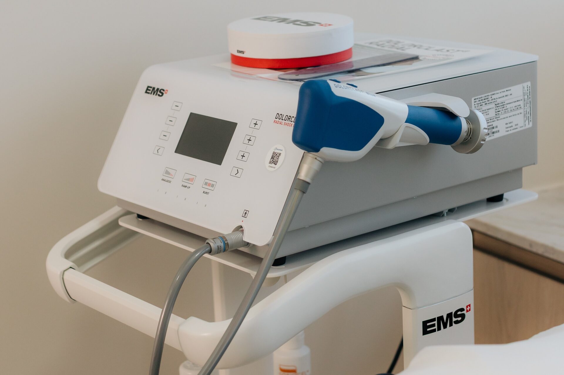 Equipamento de ondas de choque Swiss Dolorclast New na sala da Galvão Ortopedia em Londrina, console e peça de mão sobre maca vazia